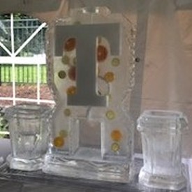 ice matters - single pour drink luge with citrus fruit frozen into block and snowfilled initial-individual bottle holder on each side