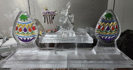 19.)  ice matters - 80 inch base tray with colored egg on each side of raised tray holding bunny with backpack - colors vary